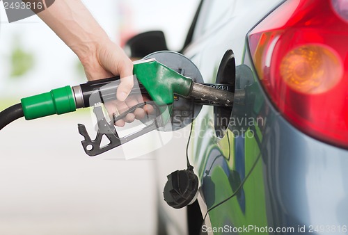 Image of man pumping gasoline fuel in car at gas station