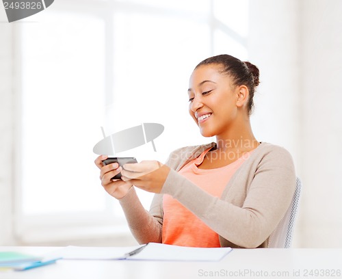 Image of african woman with smartphone in office