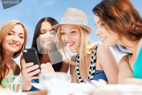 Image of girls looking at smartphone in cafe on the beach