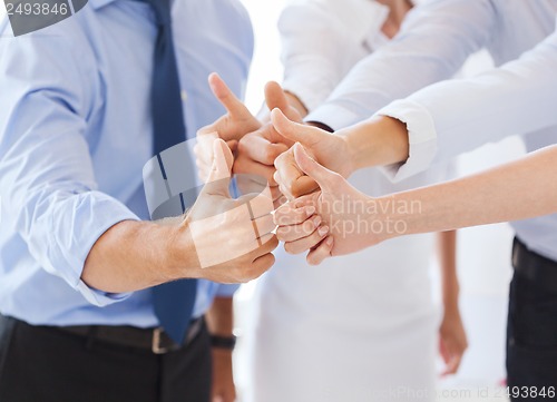 Image of business team showing thumbs up in office