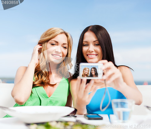 Image of girls taking photo in cafe on the beach