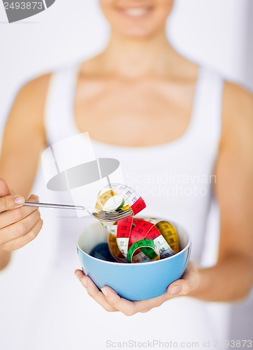 Image of woman hands holding bowl with measuring tape