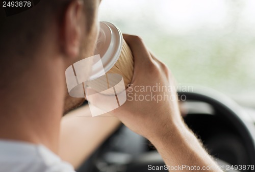 Image of man drinking coffee while driving the car