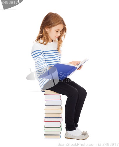 Image of little student girl sitting on stack of books