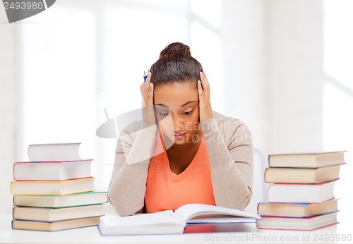 Image of tired student with books and notes