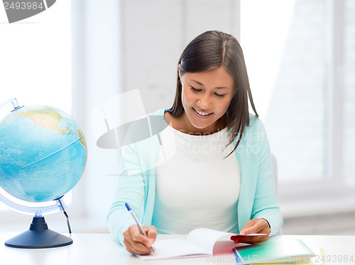 Image of teacher with globe and notepad at school