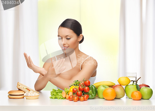 Image of woman with fruits rejecting junk food
