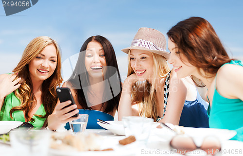 Image of girls looking at smartphone in cafe on the beach