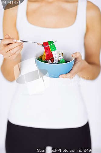 Image of woman hands holding bowl with measuring tape