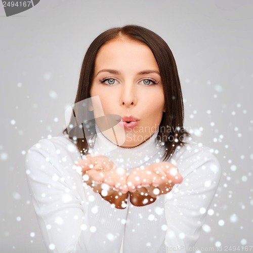 Image of happy woman in white sweater blowing on palms