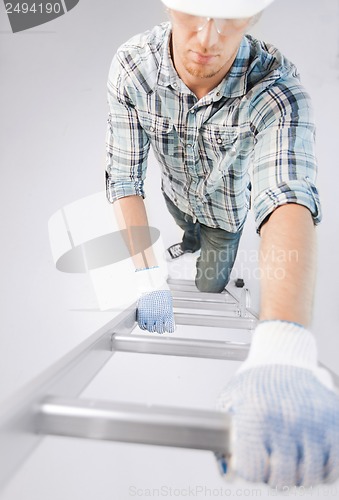 Image of man in helmet and gloves climbing ladder