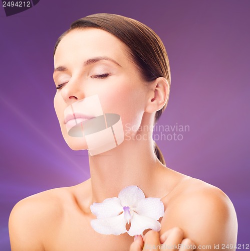 Image of relaxed woman with orhid flower