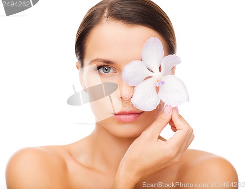 Image of relaxed woman with or??hid flower over eye