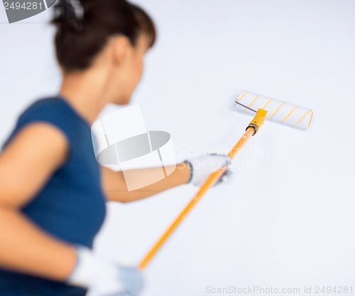 Image of woman with roller and paint colouring the wall