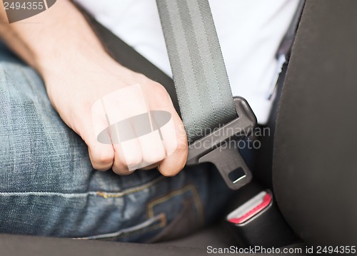 Image of man fastening seat belt in car