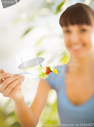 Image of woman hand holding fork with vegetables