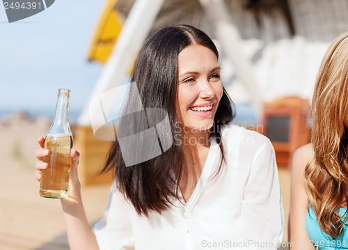 Image of girl with drink and friends on the beach