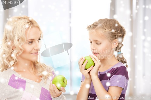 Image of mother and daughter holding green apples