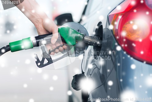 Image of man pumping gasoline fuel in car at gas station