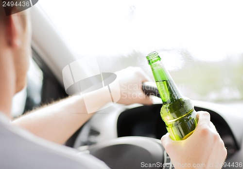 Image of man drinking alcohol while driving the car