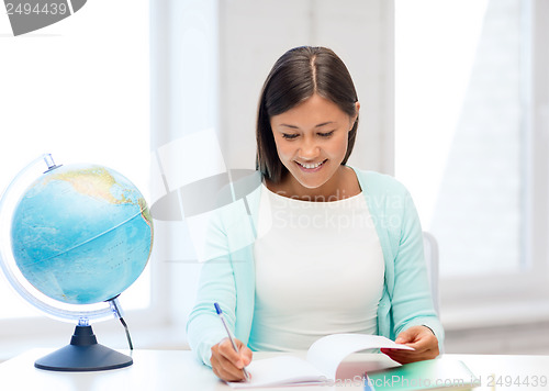 Image of teacher with globe and notepad at school