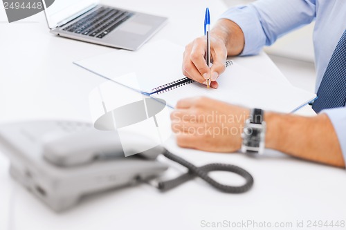 Image of businessman writing in notebook