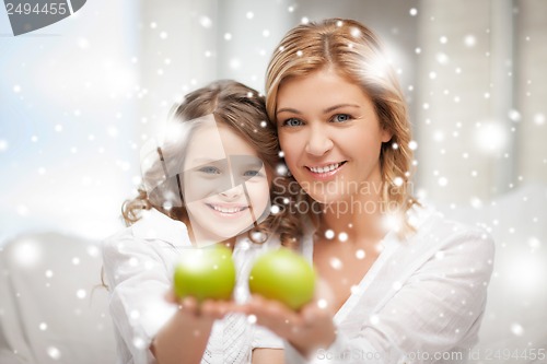 Image of mother and daughter holding green apples