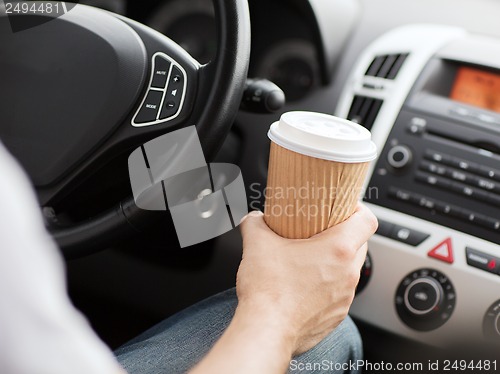 Image of man drinking coffee while driving the car