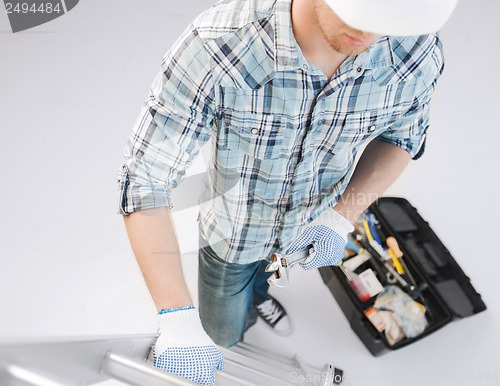 Image of man with ladder, toolkit and spanner