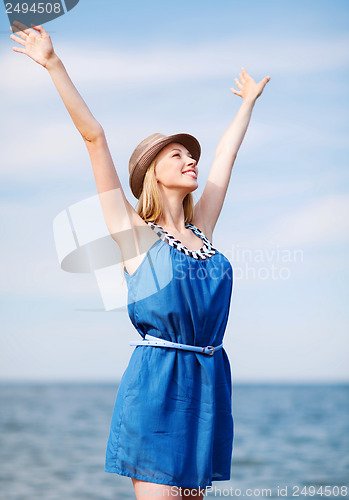 Image of girl with hands up on the beach
