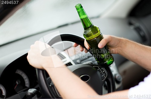 Image of man drinking alcohol while driving the car