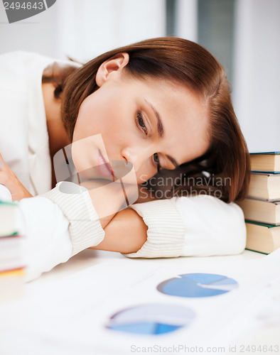 Image of bored young woman with many books and graphs