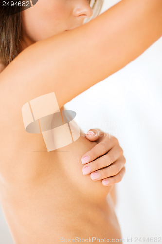 Image of woman checking breast for signs of cancer