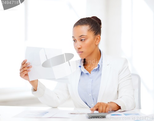 Image of businesswoman working with calculator in office