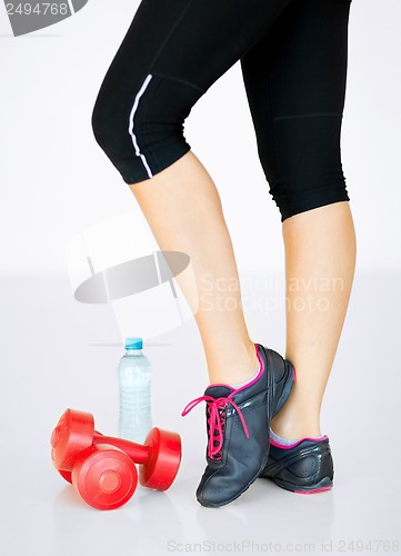 Image of sporty woman legs with light red dumbbells