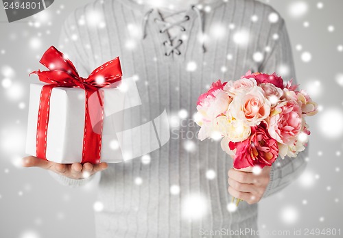 Image of man holding bouquet of flowers and gift box