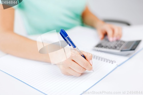 Image of businesswoman working with calculator in office