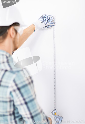 Image of architect measuring wall with flexible ruler