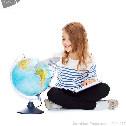 Image of child looking at globe and holding book