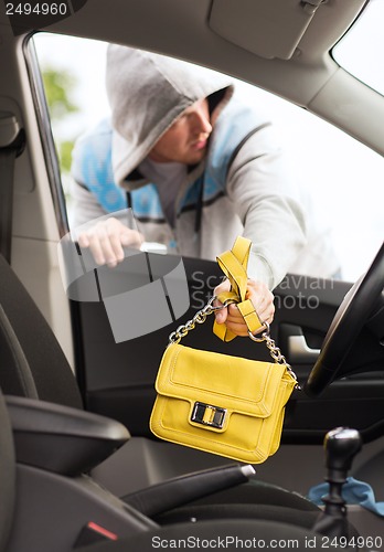 Image of thief stealing bag from the car