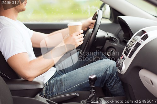 Image of man drinking coffee while driving the car