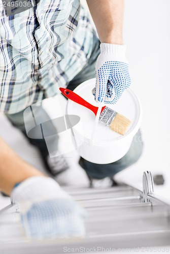 Image of man with paintbrush, pot and ladder