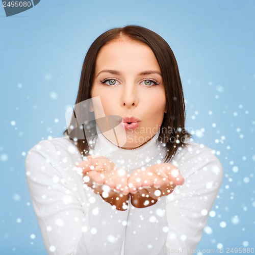 Image of happy woman in white sweater blowing on palms