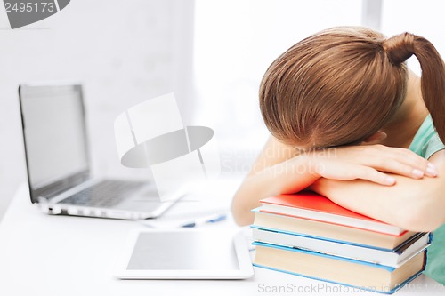 Image of tired student sleeping on stock of books