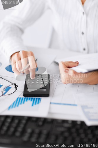 Image of woman hand with calculator and papers