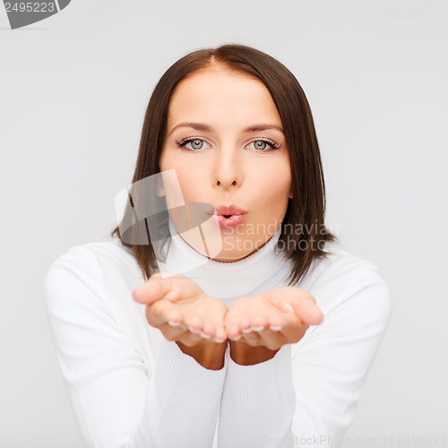 Image of happy woman in white sweater blowing on palms