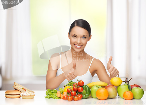 Image of woman with fruits rejecting junk food