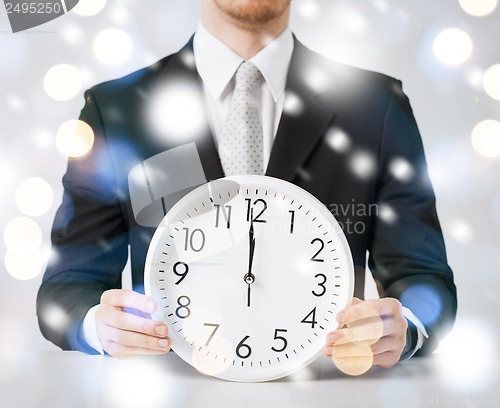 Image of man holding wall clock showing 12