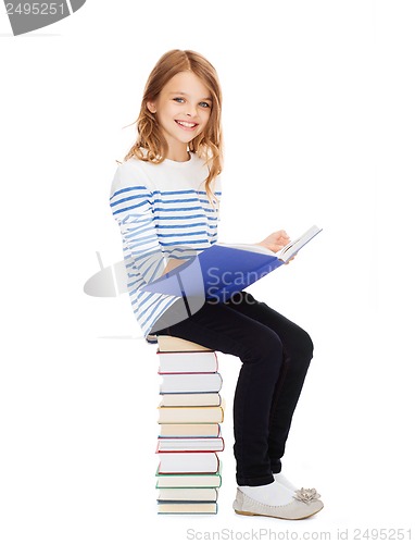 Image of little student girl sitting on stack of books