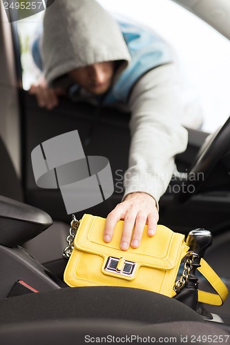 Image of thief stealing bag from the car